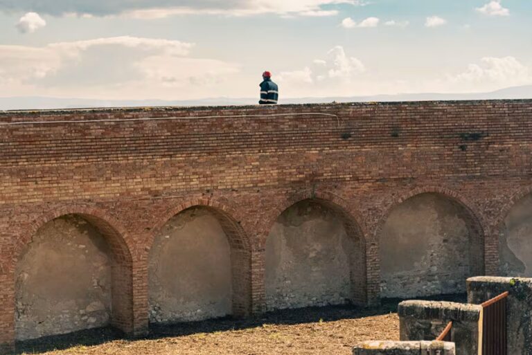 Fase di restauro delle imponenti mura storiche in mattoni e delle arcate di Excelle San Gimignano, con vista sulle colline toscane