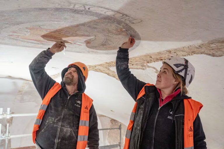 Due esperti restauratori al lavoro con precisione per il recupero di un affresco e scritte storiche in latino sulle volte di Excelle San Gimignano