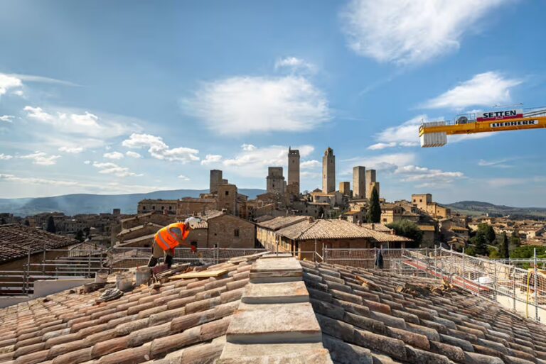 Artigiano al lavoro sul tetto di Excelle San Gimignano con i tradizionali coppi toscani e vista spettacolare sulle torri medievali