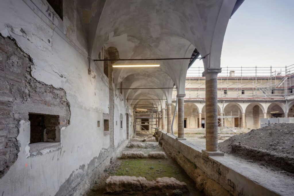 Prospettiva del loggiato interno di Excelle San Gimignano durante il restauro, con focus sulle colonne originali e le volte a crociera
